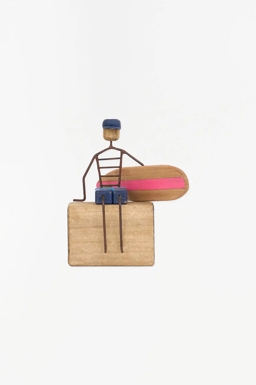 Figura de surfero sentado de metal y madera