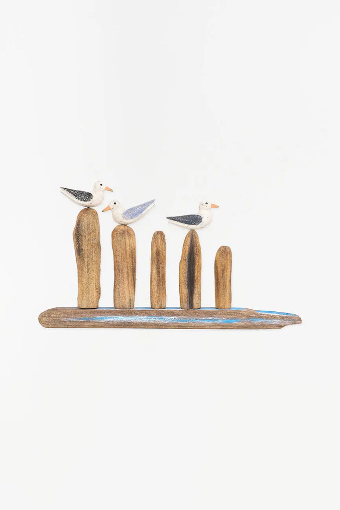 Figura de tres aves costeras sobre troncos