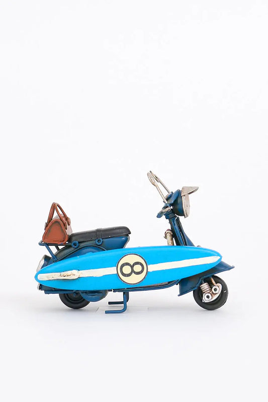 Moto vespa azul con tabla de surf