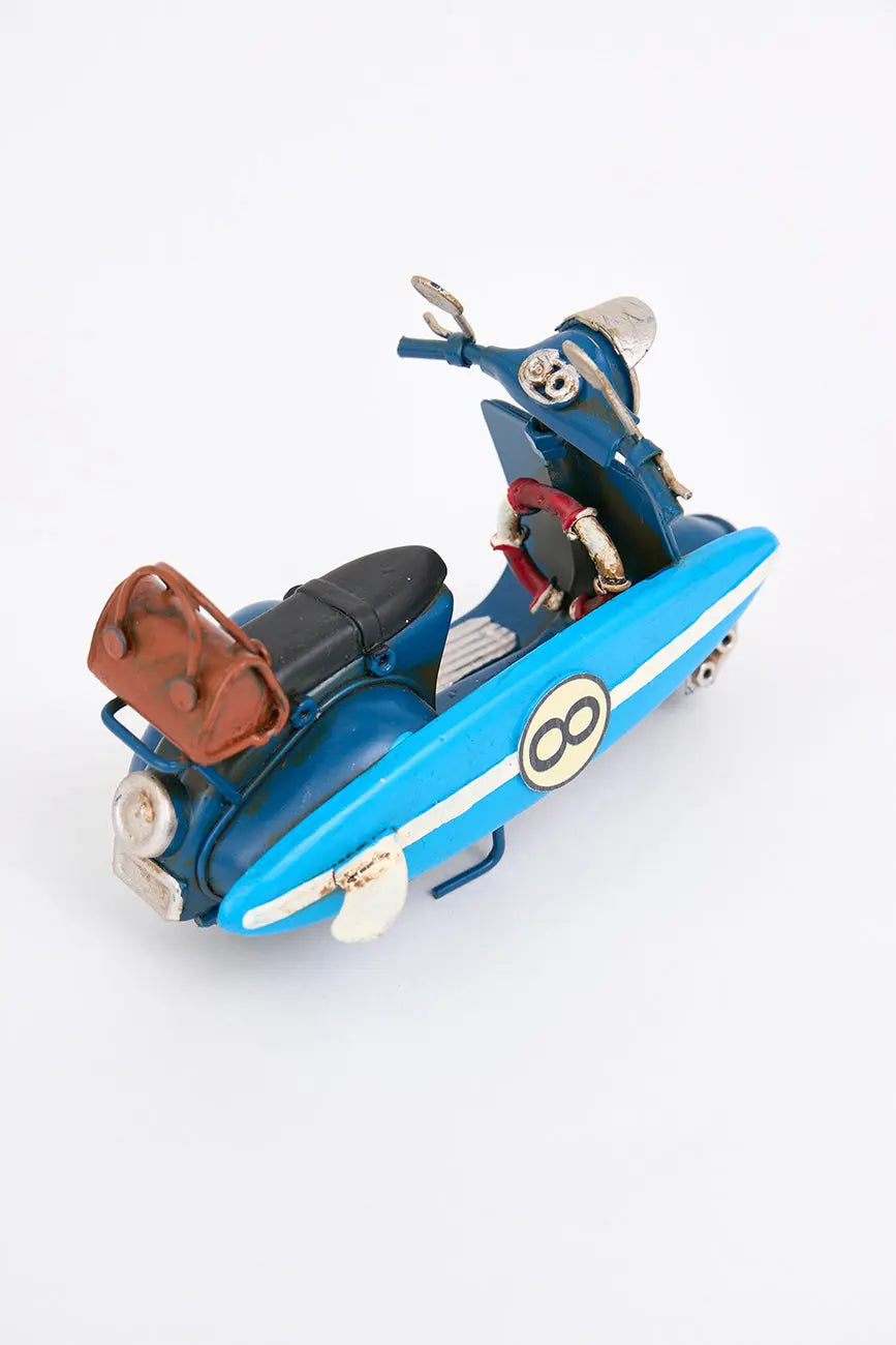 Moto vespa azul con tabla de surf