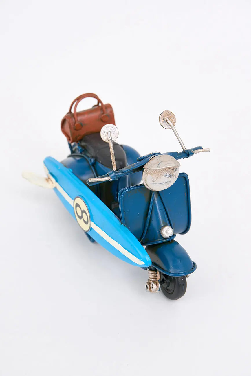 Moto vespa azul con tabla de surf
